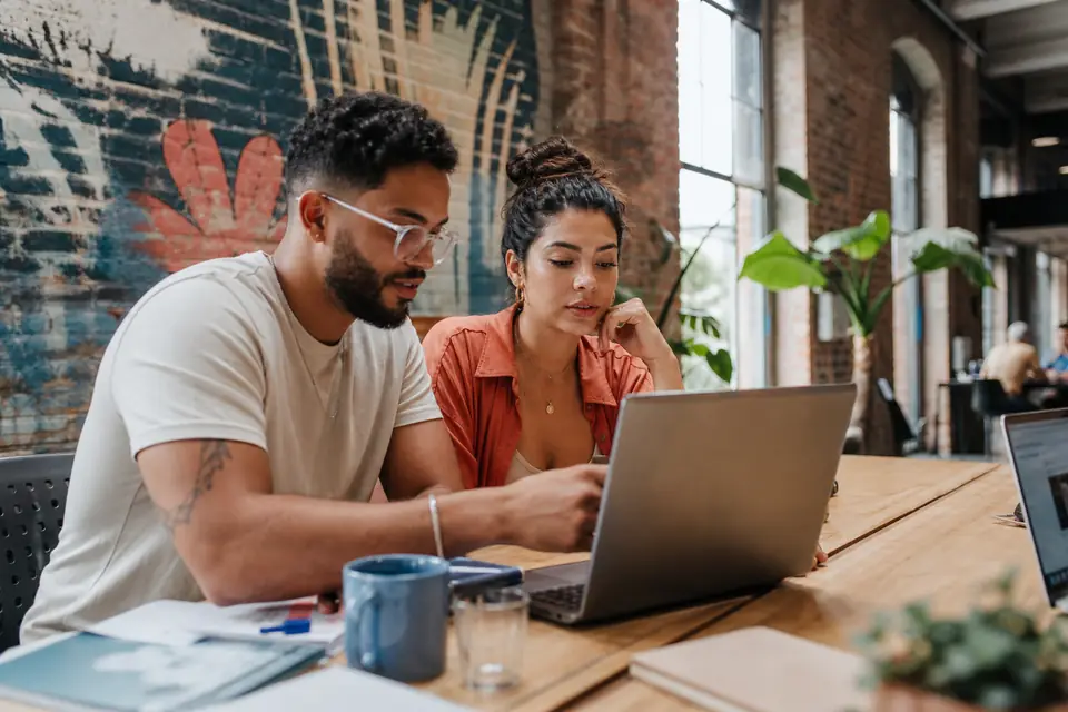 Dos profesionales jóvenes trabajan con computadoras en un espacio de coworking en Santurce